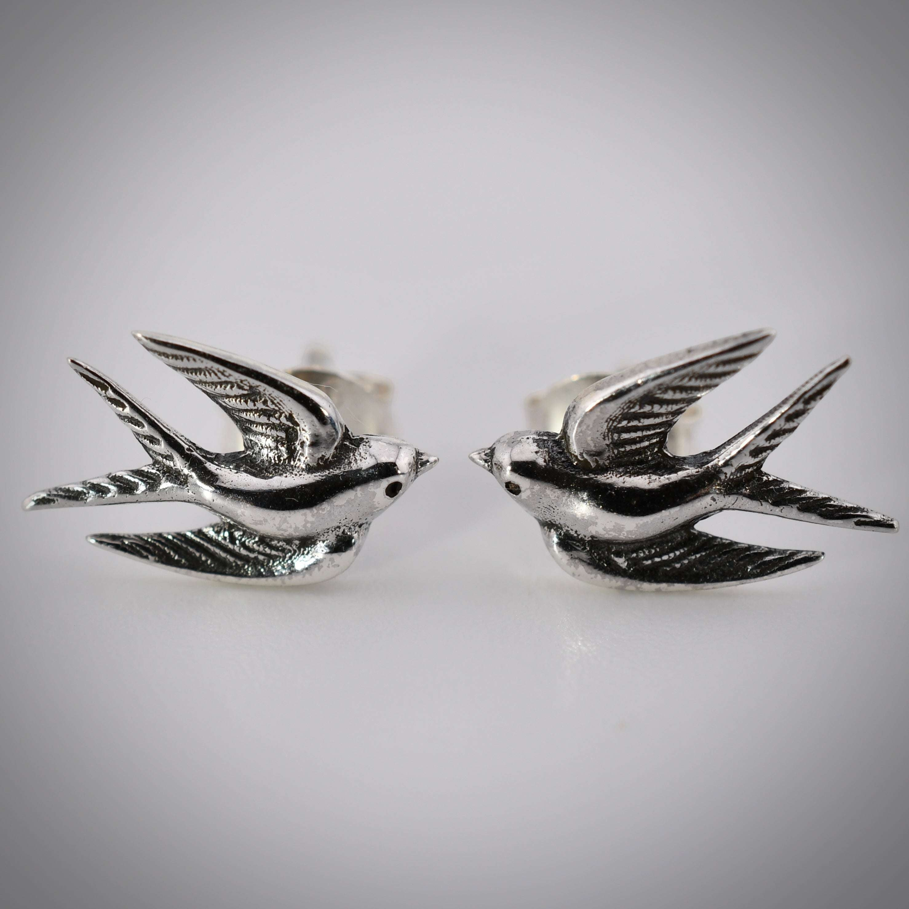 Sterling silver post earrings shaped like swallows in mid-flight, with detailed wings and bodies.