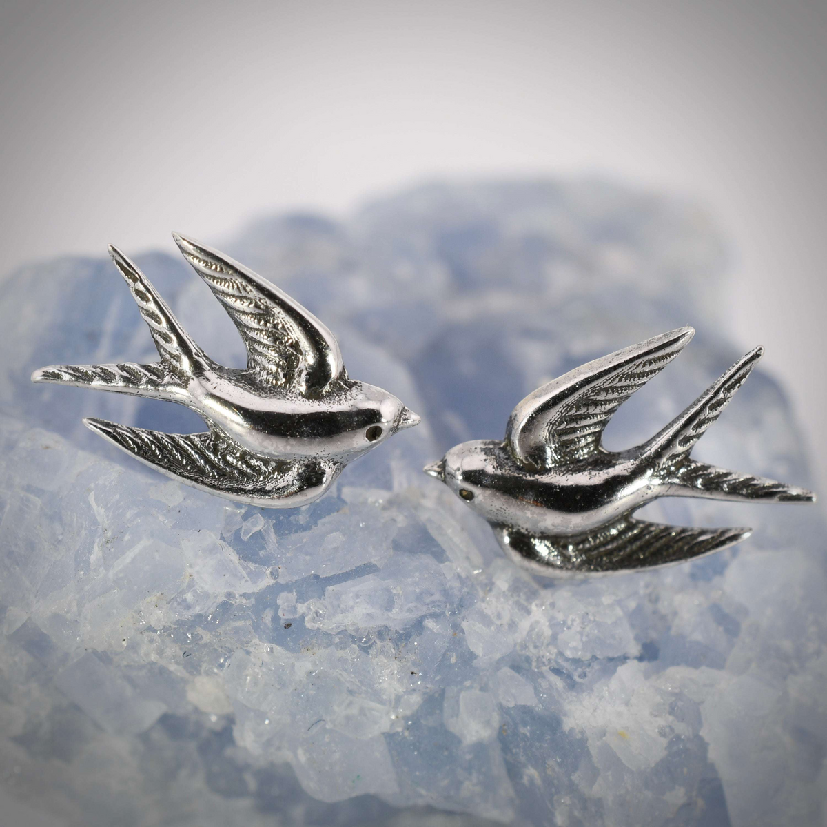 Detailed sterling silver swallow post earrings with outstretched wings, capturing a bird in mid-flight.
