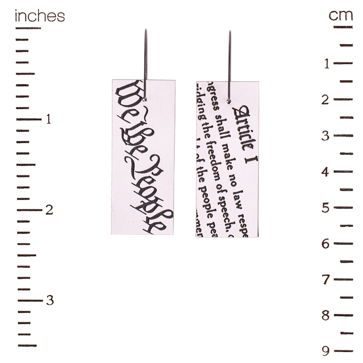 Earrings with text from the Constitution measured against a ruler.