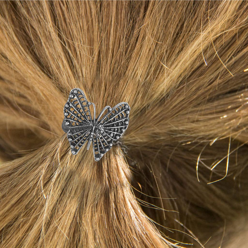Silver filigree butterfly hair tie with rhinestones, securing blonde hair in a ponytail.
