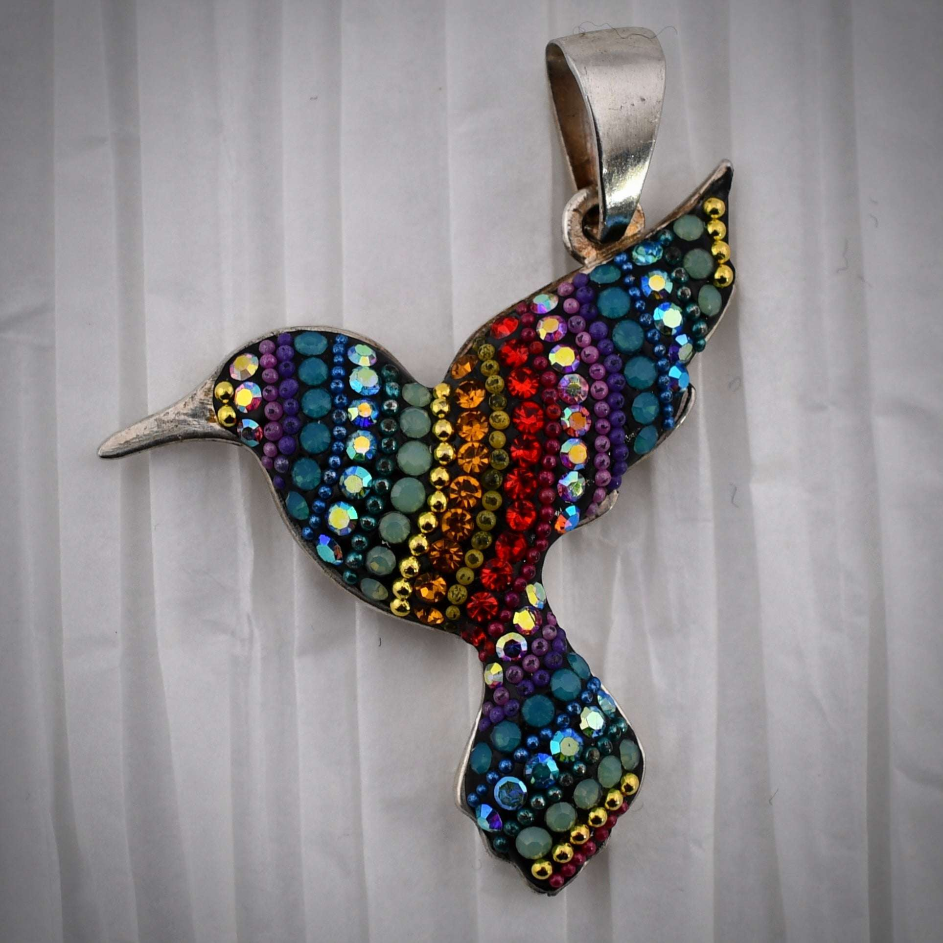 Sterling silver hummingbird pendant encrusted with colorful crystals in shades of purple, blue, teal, green, yellow, orange, and red.