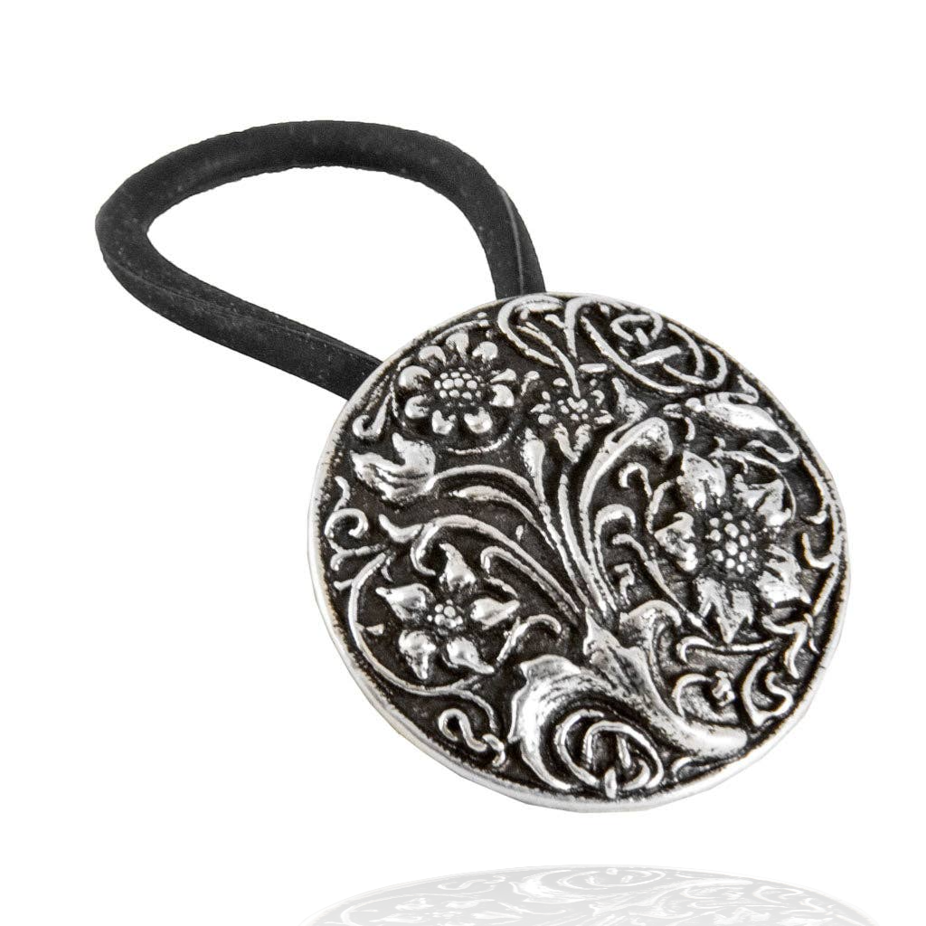 Round silver ponytail holder with a black elastic band, featuring an ornate wildflower and scroll design.
