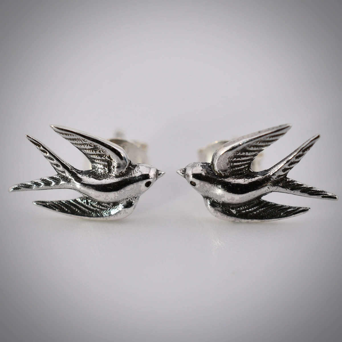 Sterling silver post earrings shaped like swallows in mid-flight, with detailed wings and bodies.